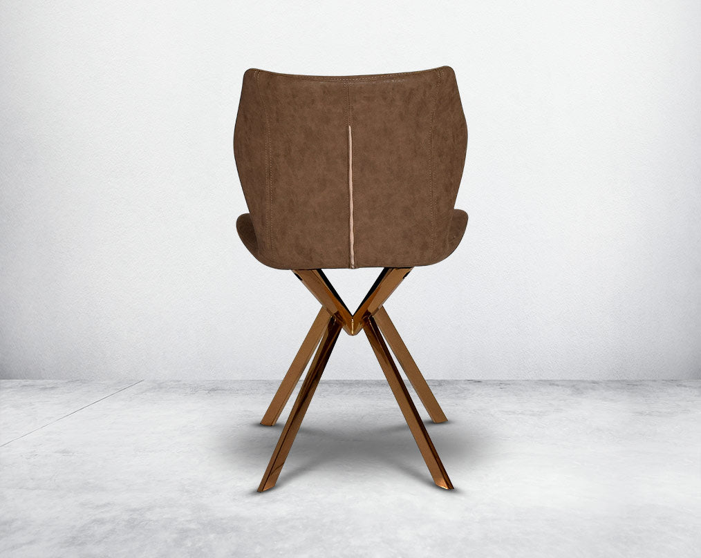 Dining chair back upholstered in faux leather with high polished stainless steel legs plated in rose gold.