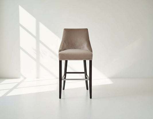 Bar chair upholstered in fabric with buttoned tufted back and silver rivets, the stool has a stainless steel front bar as a foot rest with legs in dark vintage brown wood front view
