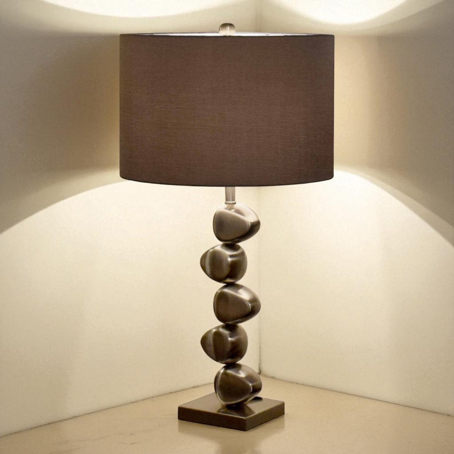 Table lamp with a brown fabric shade and stone-like base on a neutral background