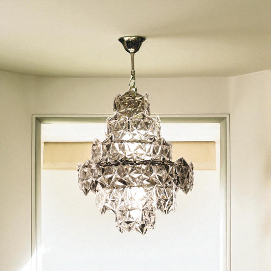Crystal chandelier hanging from a ceiling in a room with a window.