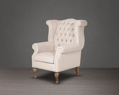 Wing arm chair upholstered in fabric with tufted back and stainless steel rivets and oak wood legs