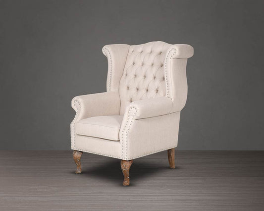Wing arm chair upholstered in fabric with tufted back and stainless steel rivets and oak wood legs