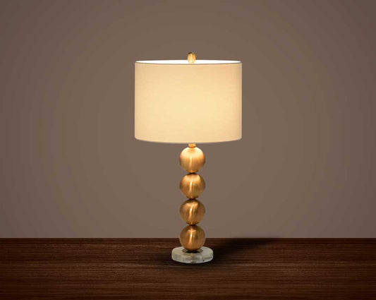 Table lamp with metallic gold and glass decorative base with translucent fabric shade.