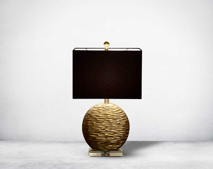 Table lamp in gold decorative glass base on a silver-plated metal stands with black fabric translucent fabric shade front view