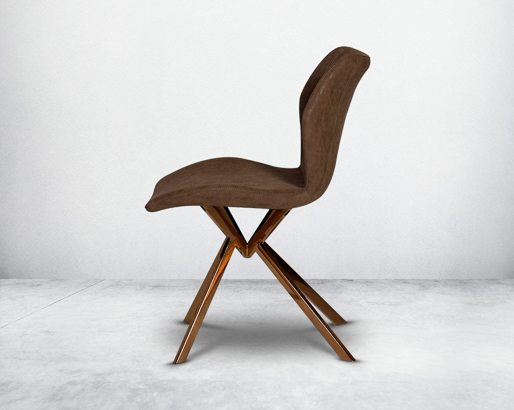 Dining chair upholstered in faux leather with high polished stainless steel legs plated in rose gold.
