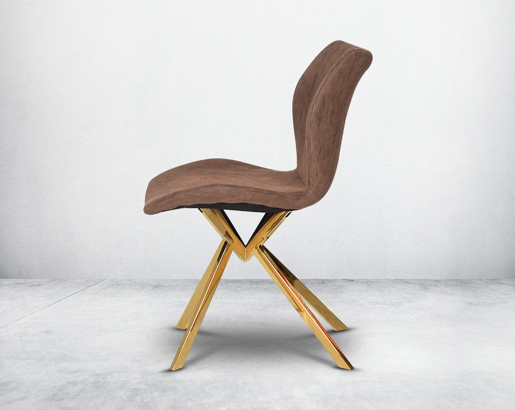 Dining chair upholstered in faux leather with high polished stainless steel legs plated in gold side view.