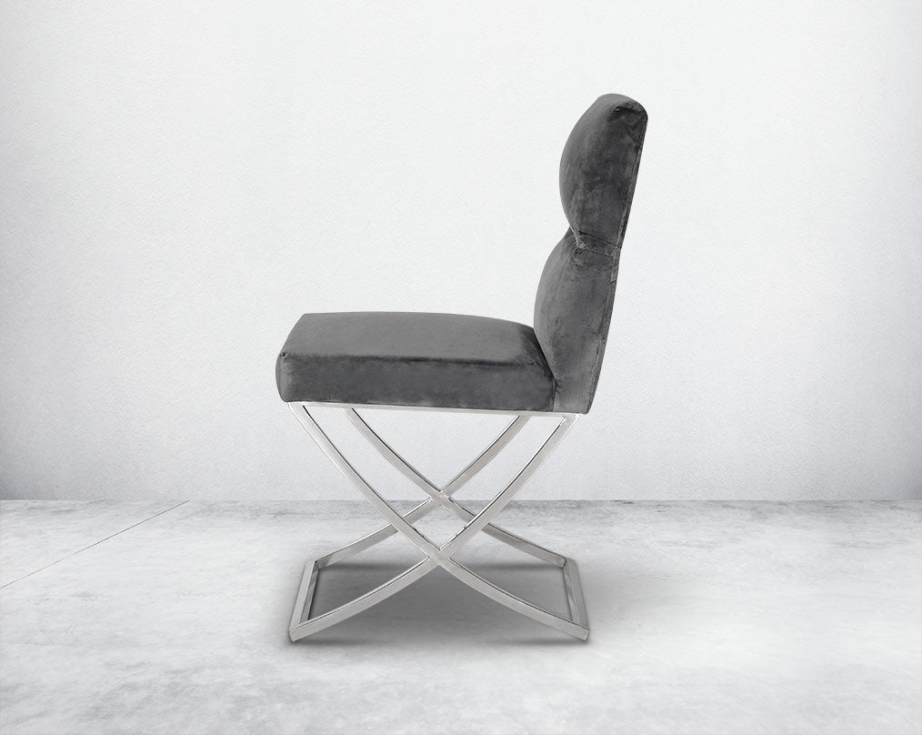 Dining chair upholstered in fabric with high polished stainless steel legs in a cross design.