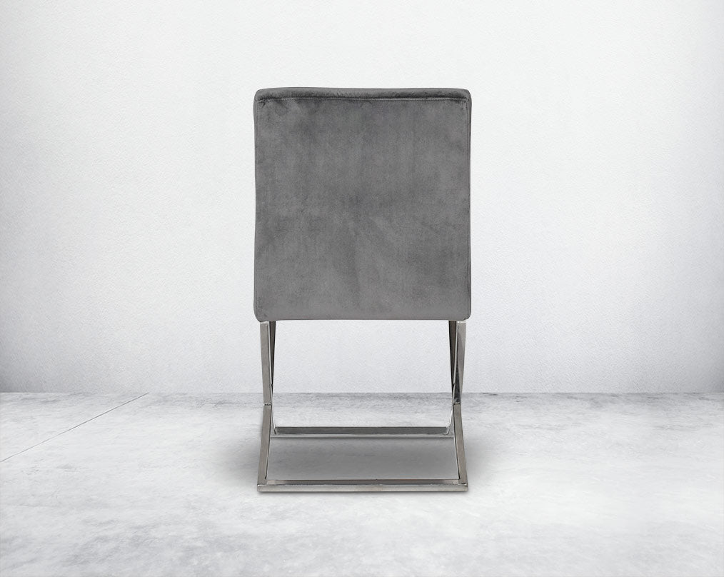 Dining chair with back upholstered in fabric with high polished stainless steel legs in a cross design.