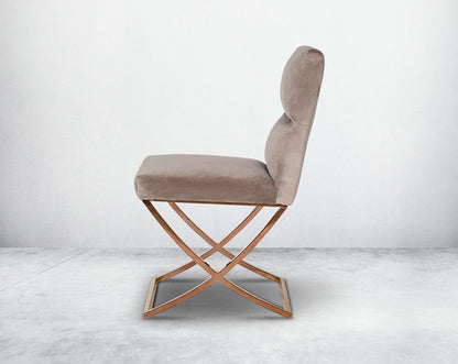 Dining chair upholstered in fabric with rose gold plated stainless steel legs in a cross design.