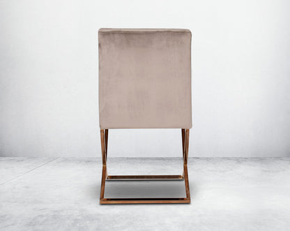 Dining chair back  upholstered in fabric with rose gold plated stainless steel legs in a cross design.