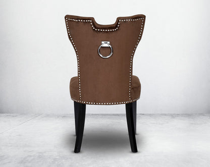 Dining chair  back upholstered in fabric with legs in wood. Stainless steel decorative ring at the back with stainless steel rivets.
