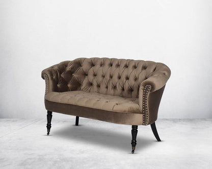 Two Seater Wing lounge chair upholstered in velvet fabric with tufted back and seat with steel rivets on the arms.