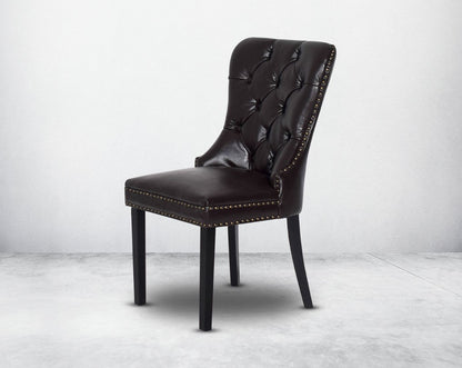 Dining chair upholstered in faux leather with buttoned tufted back the chair has antique gold rivets, legs in dark vintage brown wood.