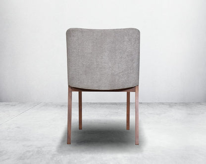 Dining chair back with upholstered in fabric with legs in walnut representing a sleek and modern style.