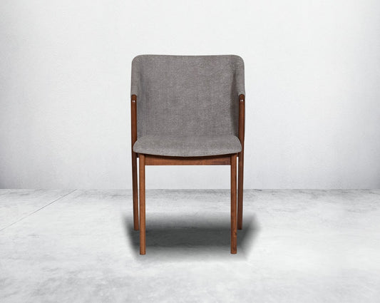 Dining chair front with upholstered in fabric with legs in walnut representing a sleek and modern style.
