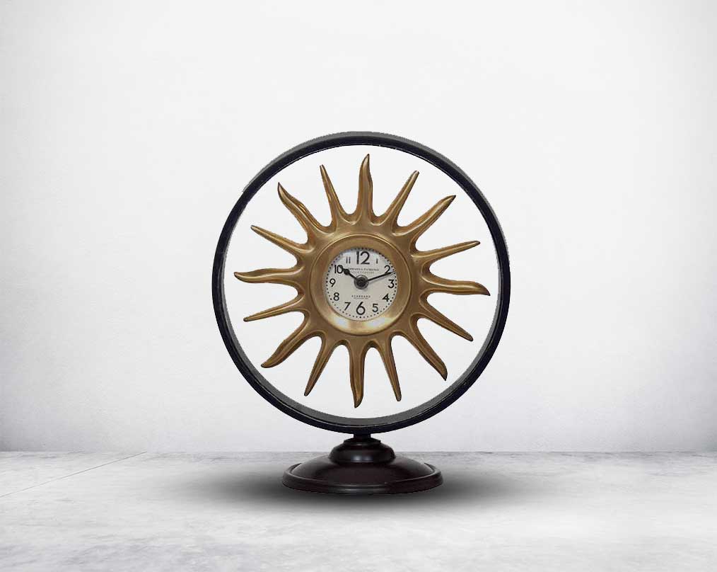 Round table clock in antique matt brass in sun ray design motif.