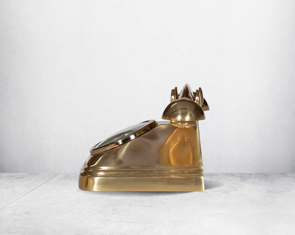 This antique clock is made out of brass in an antique matt finish It has a white dial with Roman Numerals for a vintage look