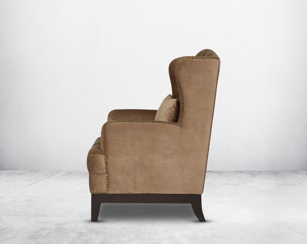 Wing arm chair upholstered in fabric and tufted with antique gold rivets on the arms and front with cushion and legs in brown oak.