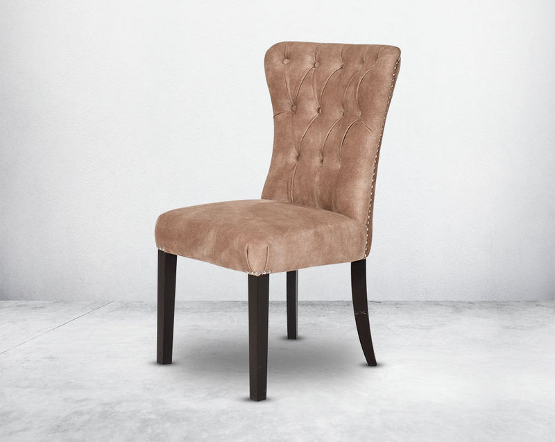 Dining chair upholstered in fabric with tufted back and birchwood legs. Stainless steel decorative ring at the back with stainless steel rivets on the sides.