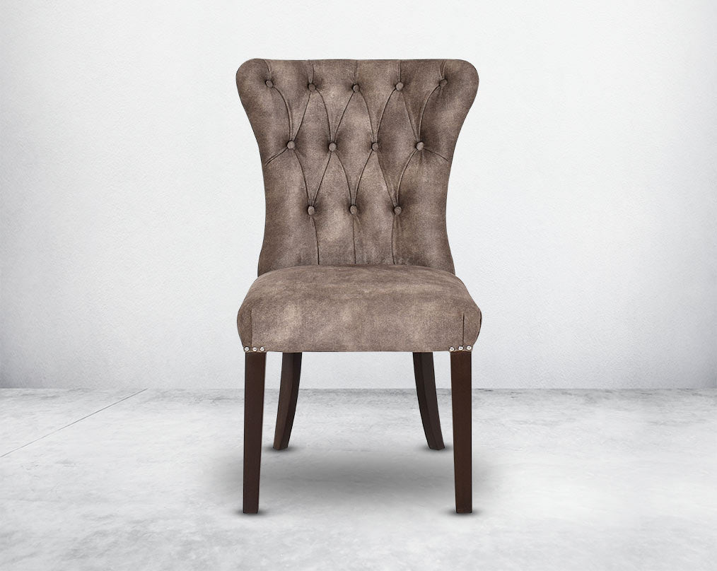 Dining chair front with upholstered in fabric with tufted back and birchwood legs. Stainless steel decorative ring at the back with stainless steel rivets on the sides.