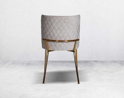 Minimalistically designed chair back with criss-cross stitch padded fabric in gold finish stainless steel legs in contemporary design.
