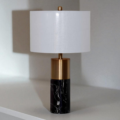 Table lamp with white shade, gold accent, and black marble base on a neutral background
