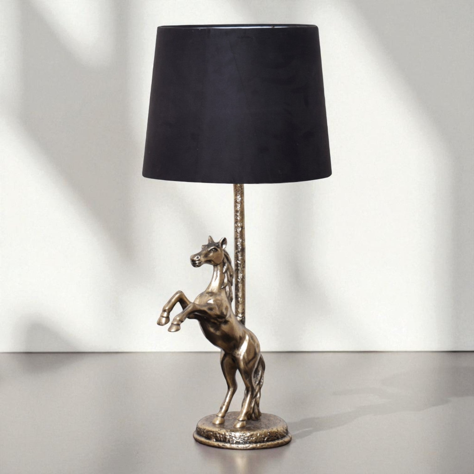 Table lamp with a horse sculpture base and black shade on a white background