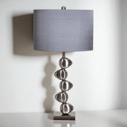 Table lamp with a gray shade and decorative base on a white background