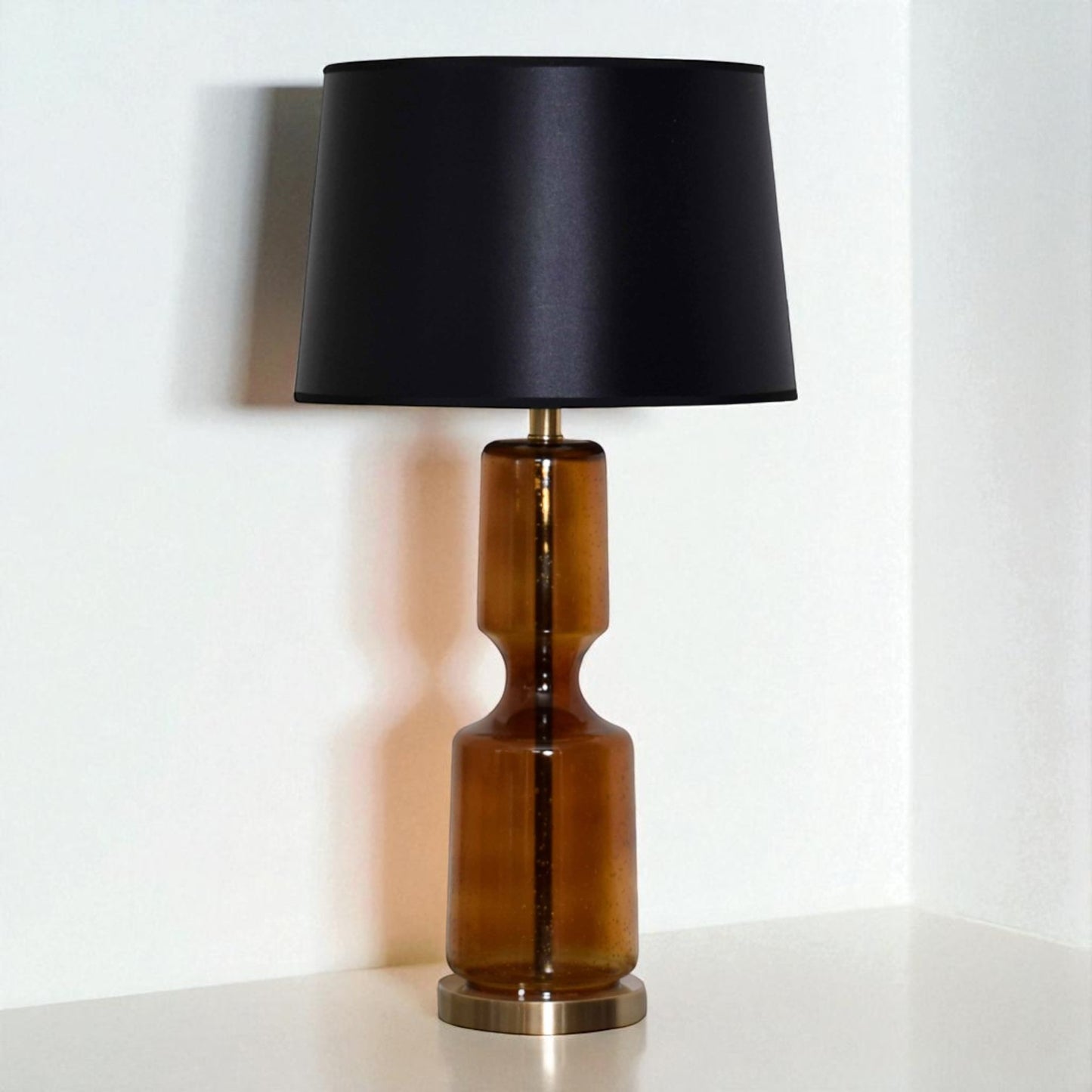 Table lamp with a black shade and brown cylindrical base on a white surface.