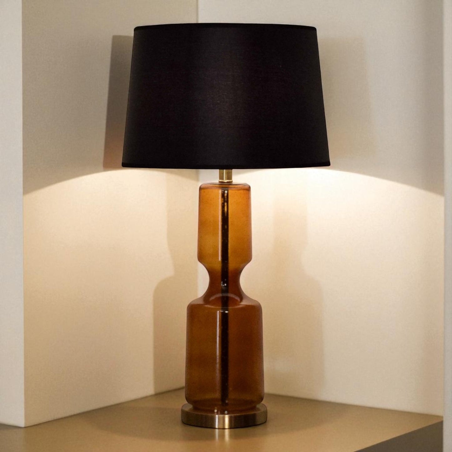 Table lamp with a black shade and brown cylindrical base on a neutral background