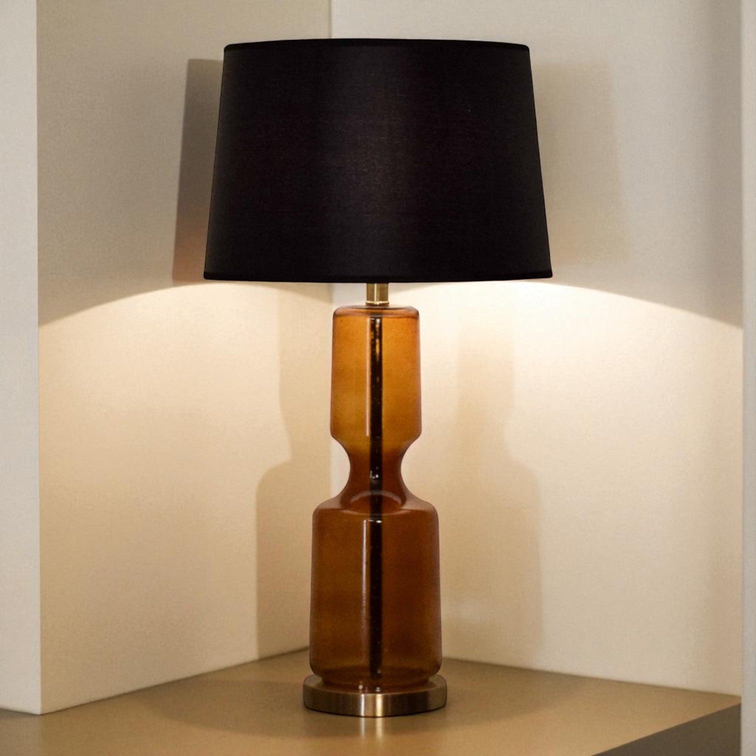 Table lamp with a black shade and brown cylindrical base on a neutral background