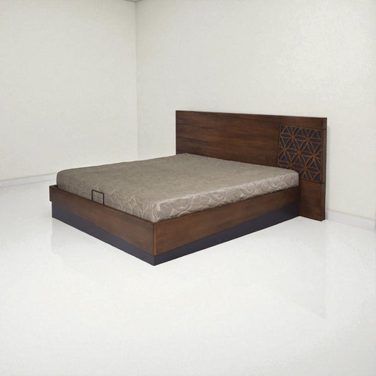 A modern wooden bed with a simple design, featuring a rectangular headboard with horizontal lines and a decorative geometric pattern on one side, placed in a minimal, white-walled room with a light-colored mattress.