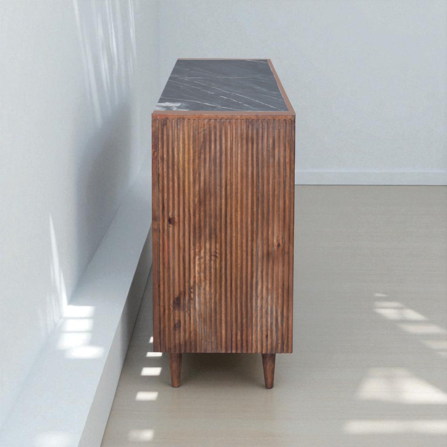 Wooden cabinet with a black marble top against a white wall