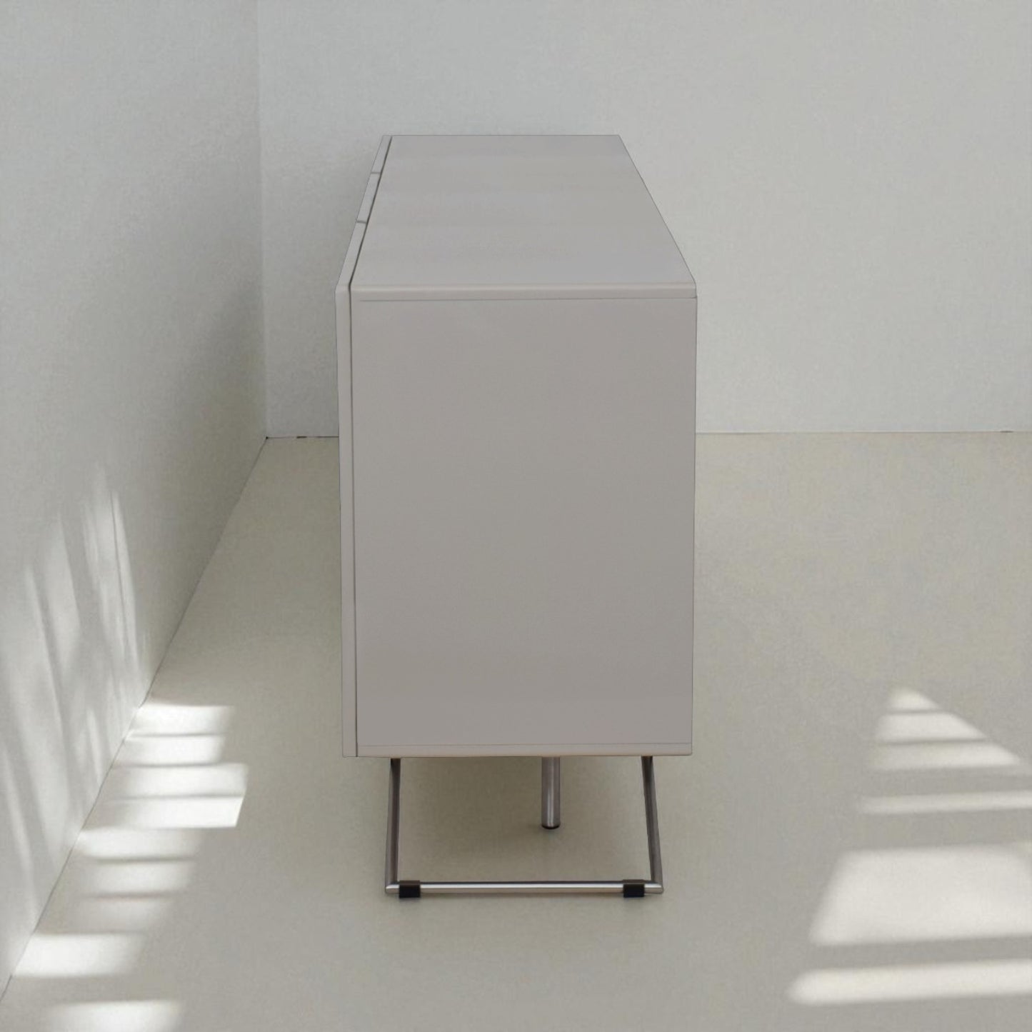 White cabinet against a white wall with sunlight casting shadows on the floor.