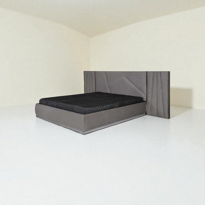 Modern grey bed with a geometric-patterned headboard and black bedding in a minimalist room.