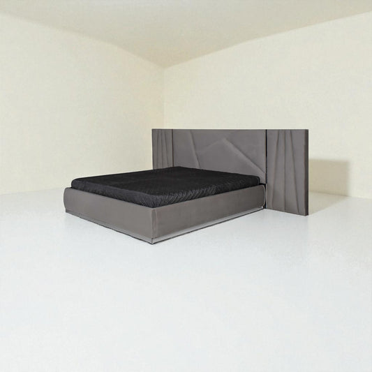 Modern grey bed with a geometric-patterned headboard and black bedding in a minimalist room.