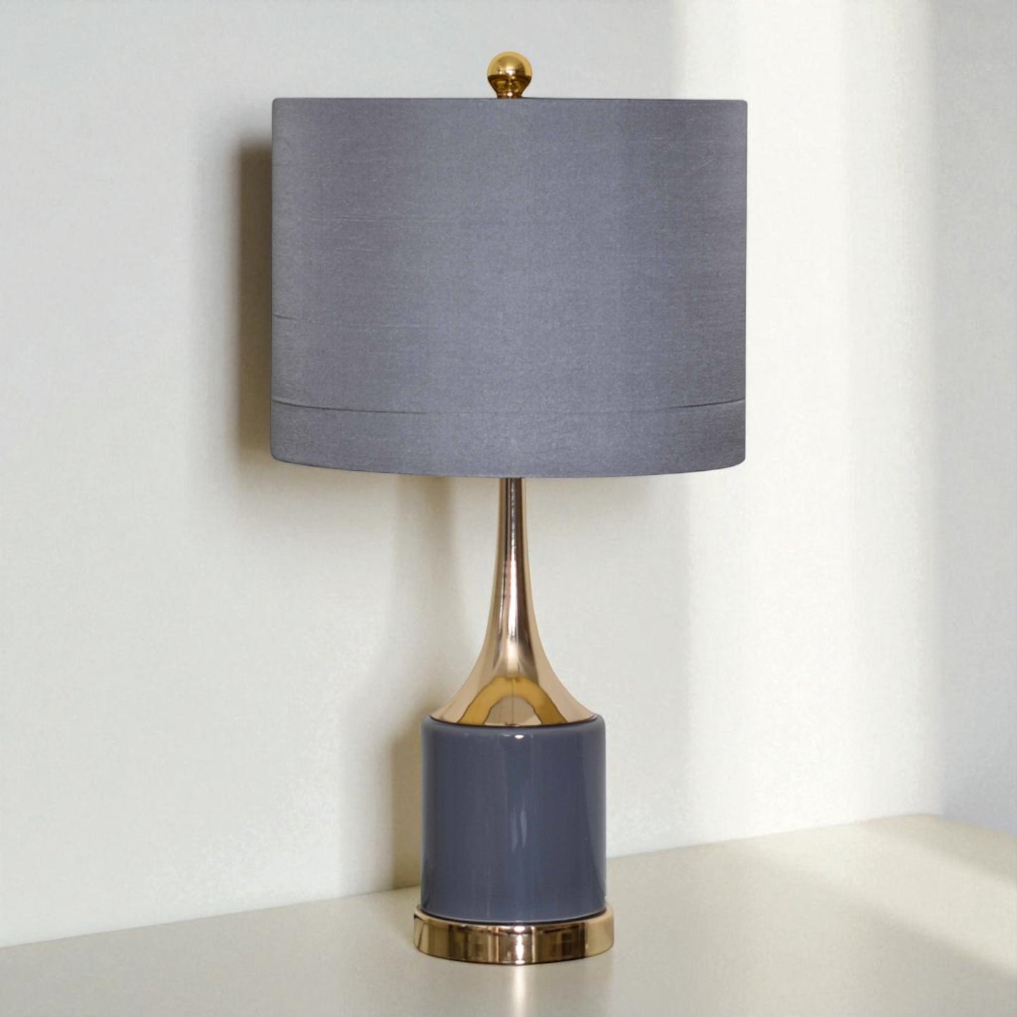 Table lamp with a gray shade and blue base on a white surface.