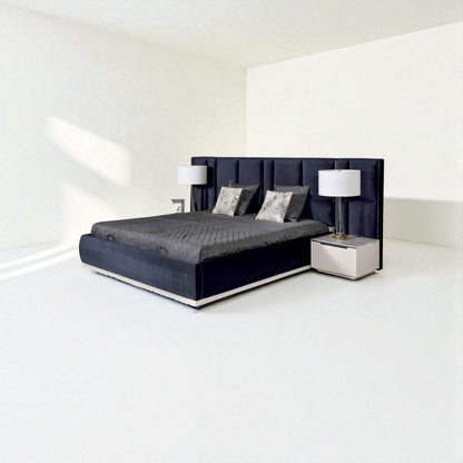 Modern dark blue bed with a tall tufted headboard, gray bedding, decorative pillows, and matching bedside tables with lamps in a minimalist room.