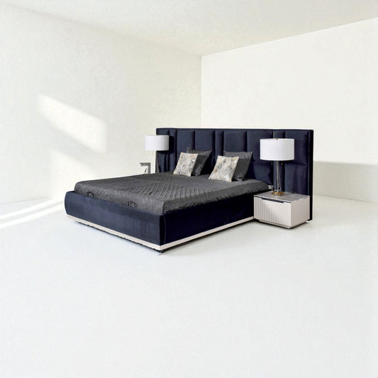 Modern dark blue bed with a tall tufted headboard, gray bedding, decorative pillows, and matching bedside tables with lamps in a minimalist room.