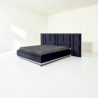 Dark blue bed with a tall panel headboard and gray bedding, set in a minimal white room.