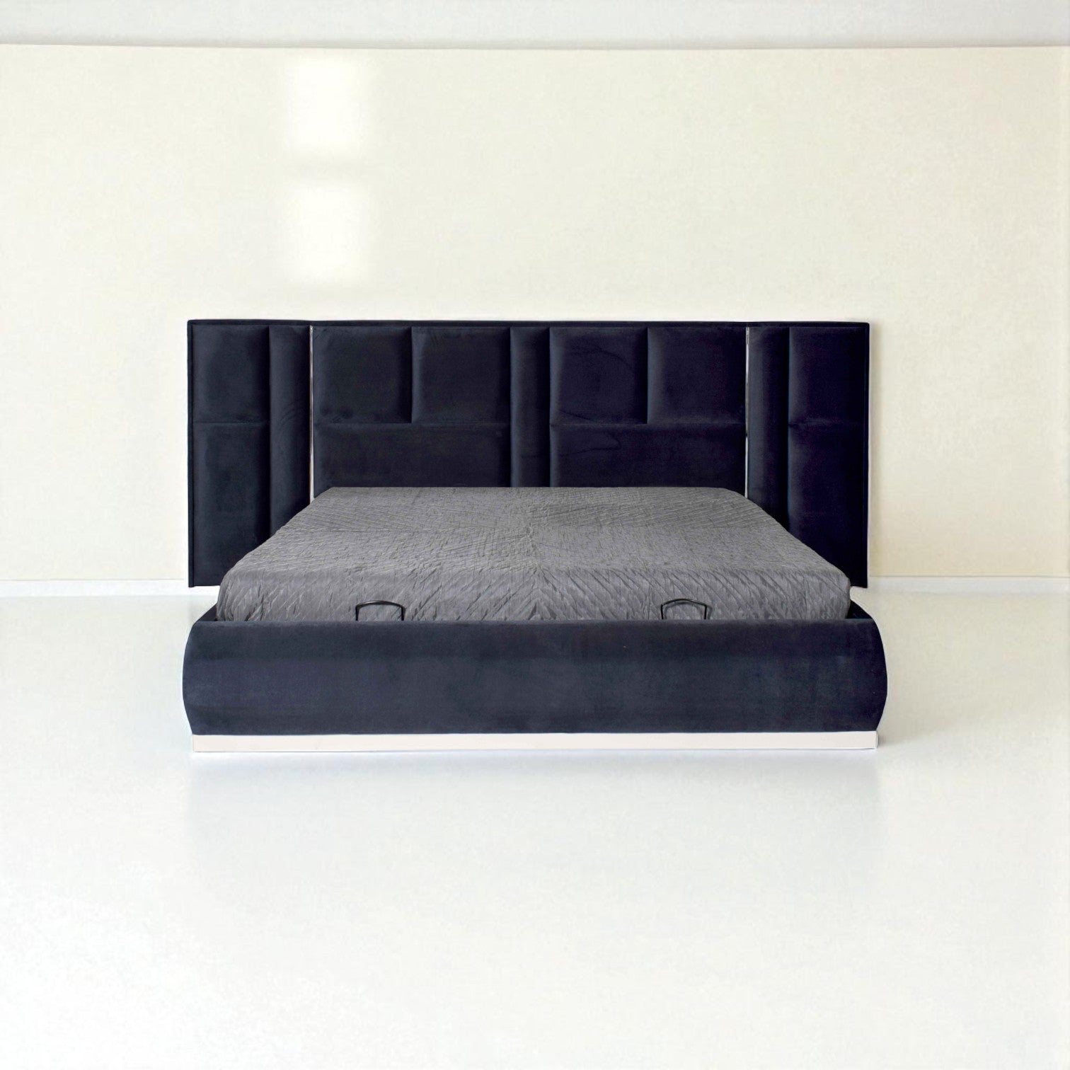 Dark blue upholstered bed with a tall panel headboard and gray bedding in a minimalist white room.