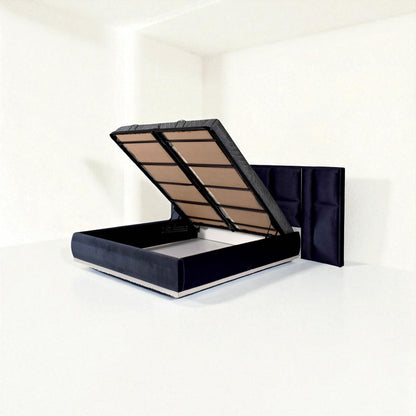 Dark blue bed with a tall panel headboard, shown with the mattress lifted to reveal under-bed storage in a bright, minimal room.