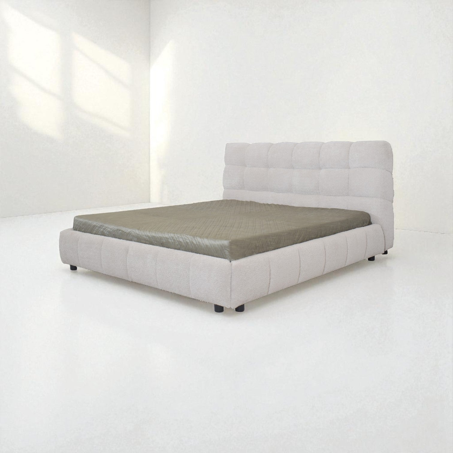 Gray upholstered bed in a minimalistic room with white walls and floor.