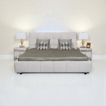 Beige upholstered bed with gray bedding and pillows in a minimalistic room.