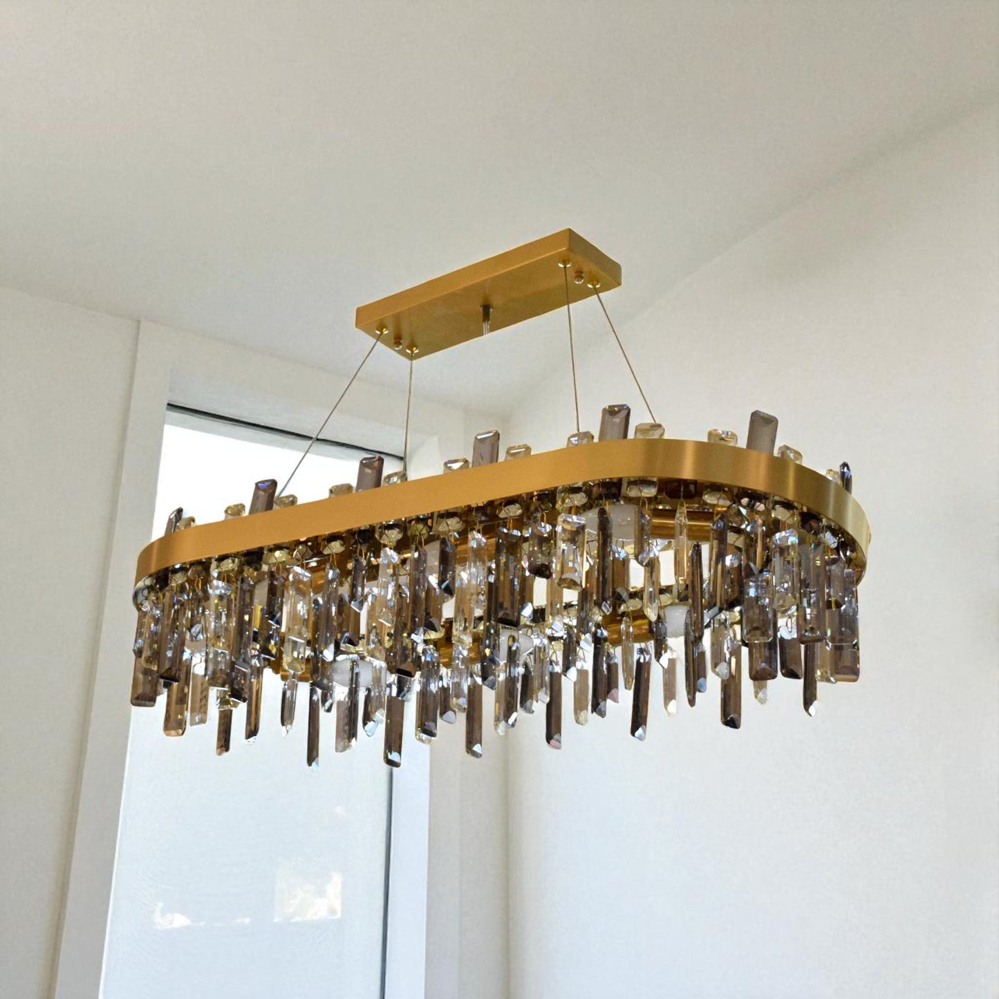 Gold chandelier with crystal accents hanging in a room with a window.