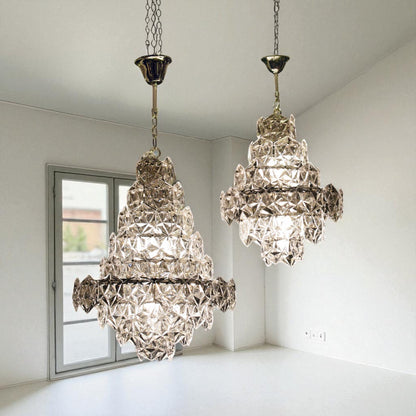 Two crystal chandeliers hanging in a room with a window.