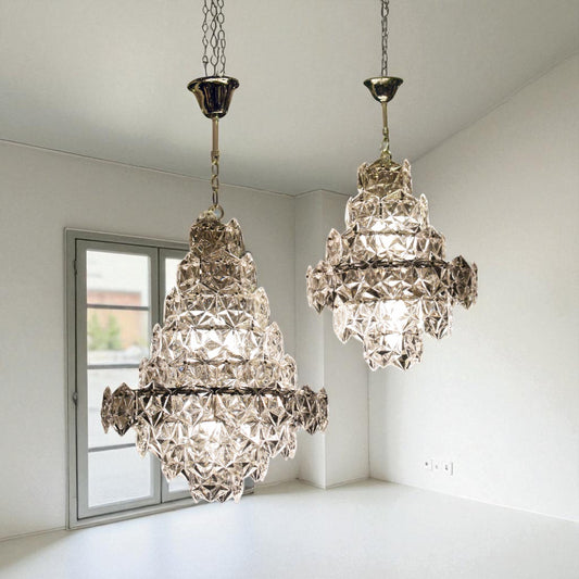 Two crystal chandeliers hanging in a room with a window.
