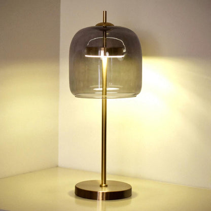 Table lamp with glass shade and brass base on a neutral background