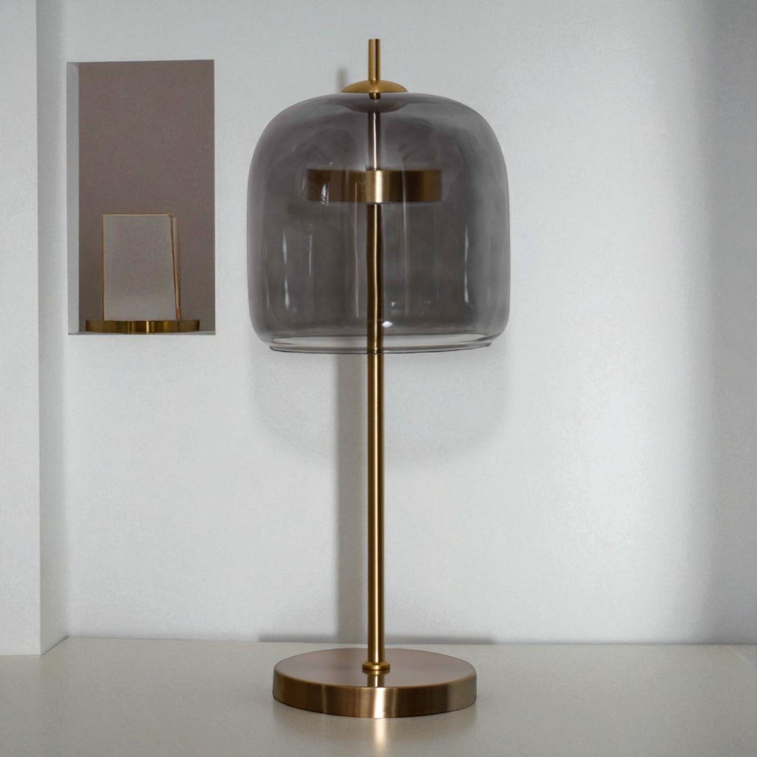 Table lamp with smoked glass shade and brass base on a neutral background