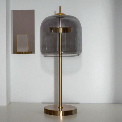 Table lamp with smoked glass shade and brass base on a neutral background